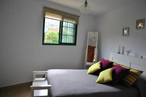 1 dormitorio con 1 cama con almohadas amarillas y moradas en Casa Bermudez, en Breña Alta