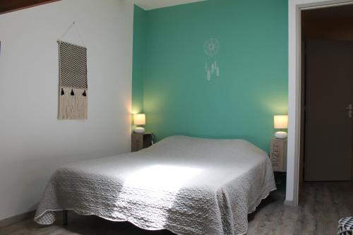 a bedroom with a white bed and a blue wall at GITES CLODEGUY No 2 in Saint-Sylvestre-sur-Lot