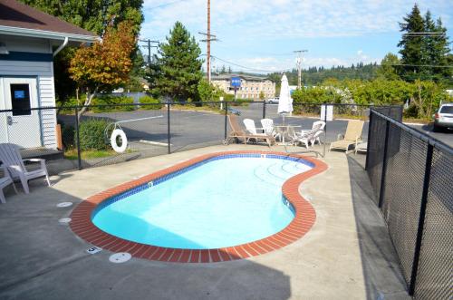 a swimming pool with a fence and chairs around it at Bellingham Lodge in Bellingham
