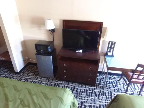 a living room with a tv on a wooden dresser with a tvictericter at Cross Road Motel in Trenton