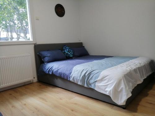a bed with blue and white sheets and a window at Villa Sunshine in Bagneux