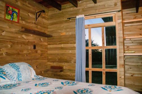 a bedroom with a window in a log cabin at Cabañas ecológicas Xuetama in Villa de Leyva