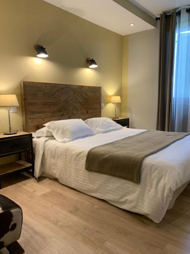a bedroom with a large bed with a wooden headboard at Hotel Berneron in Vallon-Pont-dʼArc