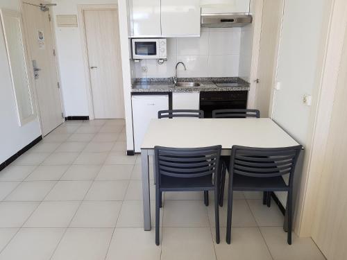 a kitchen with a table and chairs and a refrigerator at Apartamentos Maria Victoria in Benidorm