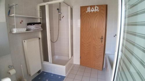 uma casa de banho com um chuveiro e uma porta de madeira em Fewo Fischer em Göppingen