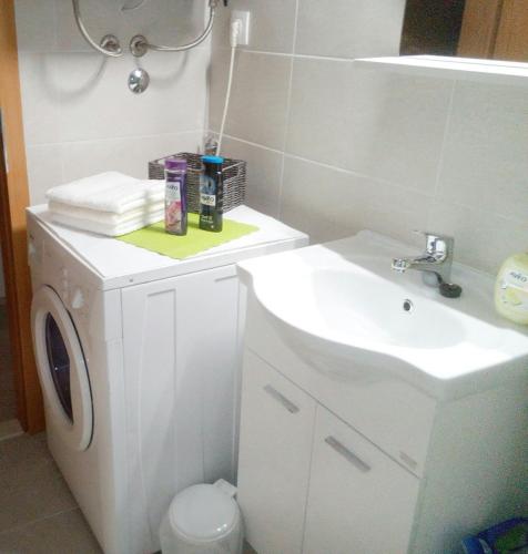 a white bathroom with a sink and a washing machine at Pavlić 2 in Omiš