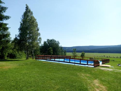 a house with a swimming pool in a grass field at Chalupa Na Paloučku in Orlické Záhoří 