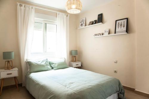 a white bedroom with a bed and a window at Akutuna - Casa Familiar con Piscina , Garaje & Pista de Padel in Zahara de los Atunes