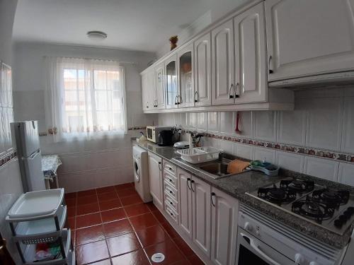 a kitchen with white cabinets and a stove top oven at Refugio das Matas in Porto Santo