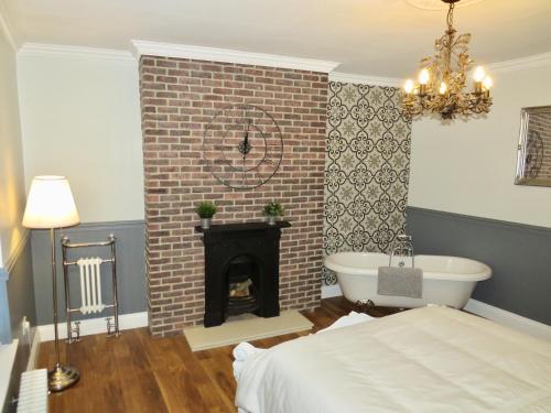 1 dormitorio con chimenea, 1 cama y bañera en Last Cottage en Newbiggin-by-the-Sea