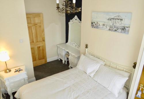 una camera con letto bianco e specchio di Last Cottage a Newbiggin-by-the-Sea