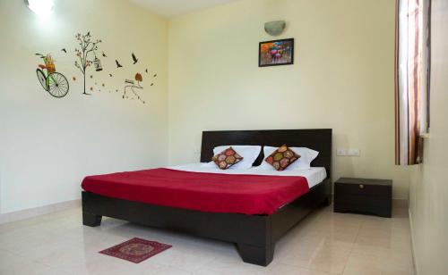 een slaapkamer met een groot bed en een rode deken bij Laxmi's Apartment - Coconut Grove Residence in Orlim