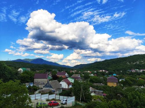 a view of a town with mountains and clouds at Rodnoy Prichal Guest House in Arkhipo-Osipovka