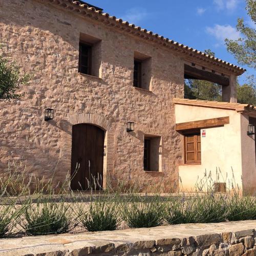 an old stone building with a door in the side at CAL PUIG, ENOTURISMO RURAL entre Viñas y Bosques in Juncosa