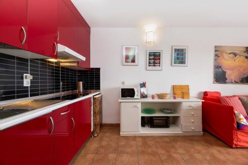 a kitchen with red cabinets and a red couch at The Colors House, 639 Private Apartment in Costa Teguise