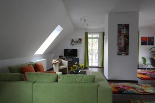a living room with a green couch and a tv at Röblinseeterrassen in Fürstenberg-Havel