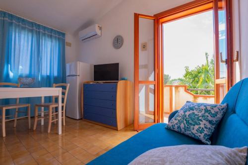 a living room with a blue couch and a table and a window at Sun & Sea, holidays home in Fontane Bianche