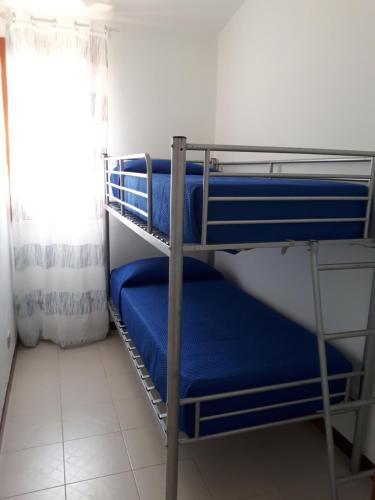 a bunk room with blue bunk beds and a window at Sun & Sea, holidays home in Fontane Bianche