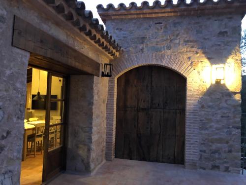 a large wooden door in a brick wall at CAL PUIG, ENOTURISMO RURAL entre Viñas y Bosques in Juncosa