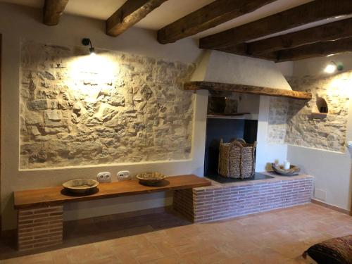 a kitchen with a stone wall with a table and a stove at CAL PUIG, ENOTURISMO RURAL entre Viñas y Bosques in Juncosa