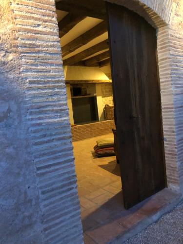 an open door to a room with a brick wall at CAL PUIG, ENOTURISMO RURAL entre Viñas y Bosques in Juncosa