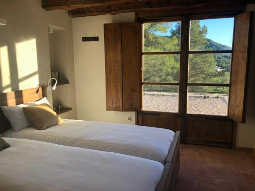 a bedroom with two beds and a large window at CAL PUIG, ENOTURISMO RURAL entre Viñas y Bosques in Juncosa