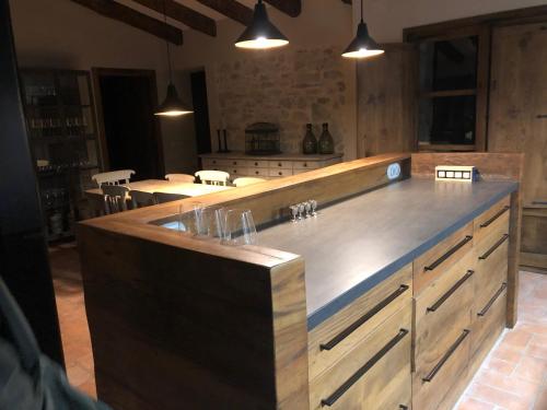 a kitchen with a large wooden counter top with lights at CAL PUIG, ENOTURISMO RURAL entre Viñas y Bosques in Juncosa