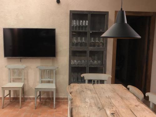 a dining room with a table and chairs and a television at CAL PUIG, ENOTURISMO RURAL entre Viñas y Bosques in Juncosa