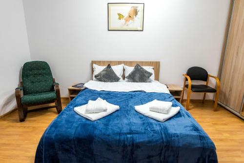 a bedroom with a blue bed with two chairs at D&O Zola in Timişoara