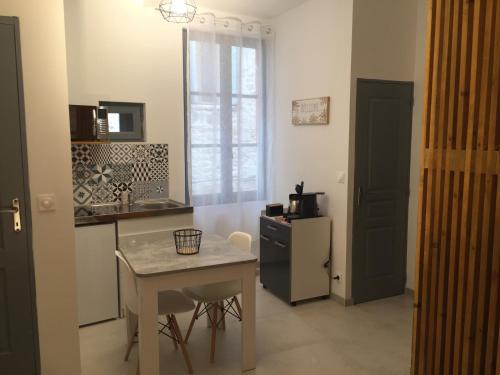 eine Küche mit einem kleinen Tisch und einem kleinen Kühlschrank in der Unterkunft Studio climatisé, La Cloison in Arles