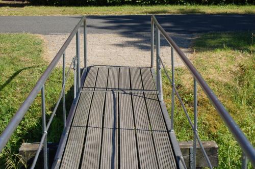 a wooden bridge with a metal gate on a road at Ferienwohnung Wiekenblick in Wiesmoor