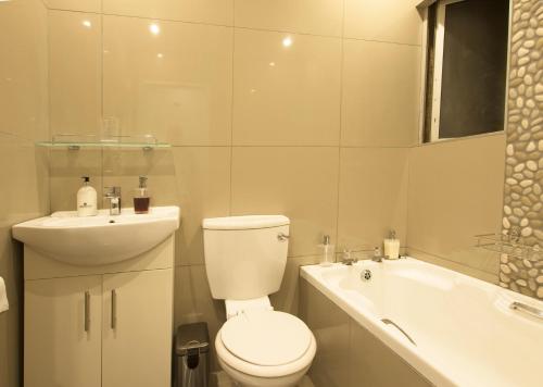 a white bathroom with a toilet and a sink at Modern Seaview Apartment in Summerstrand