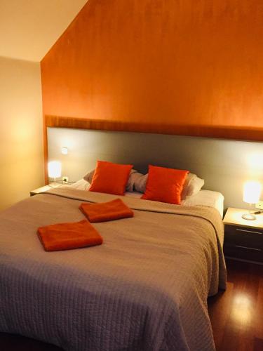 a bedroom with a large bed with orange pillows at Atrium Panzio in Esztergom