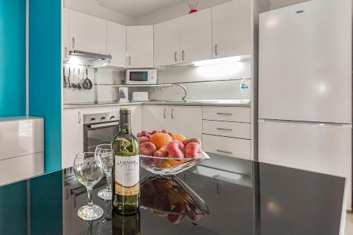 a bottle of wine and a bowl of fruit on a kitchen counter at Apartamento en Alcalá, con aparcamento, con aircondicionador in Alcalá