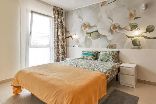 1 dormitorio con 1 cama con flores en la pared en Apartamento nuevo en Alcalá, con aparcamento, con aircondicionador, en Alcalá
