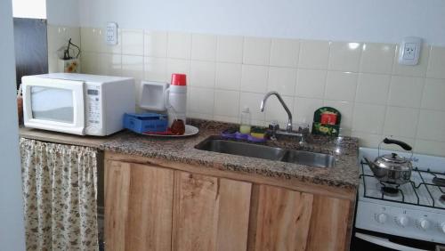 a kitchen counter with a microwave and a sink at KURMI in Olavarría