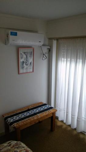 a room with a bed and a window and a bench at KURMI in Olavarría
