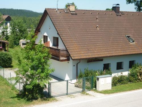 a white house with a brown roof and a fence at Pod Smrcinou in Nová Pec
