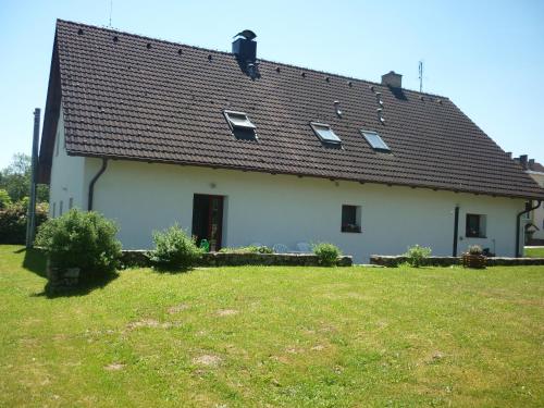 a large white house with a grass yard at Pod Smrcinou in Nová Pec