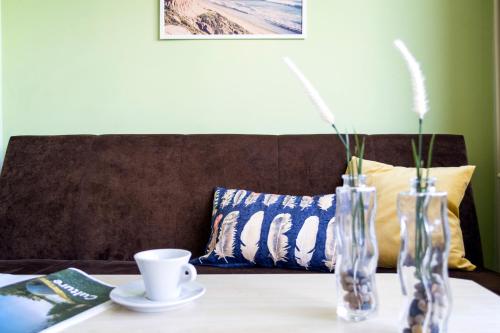 a table with two vases and a cup on a couch at Apartament Kremowy - blisko morza i Sopotu in Gdańsk