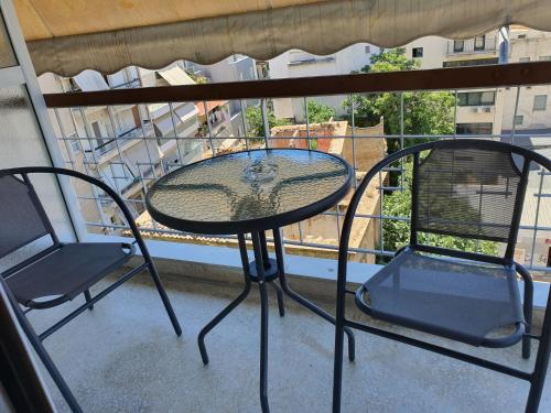 a glass table and two chairs on a balcony at City Centre Stylish rooms in Athens