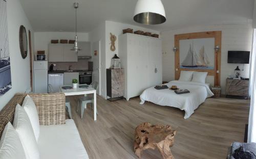 a bedroom with a bed and a kitchen with a sailboat on the wall at Nos Îles in Saint-Jean-de-Monts