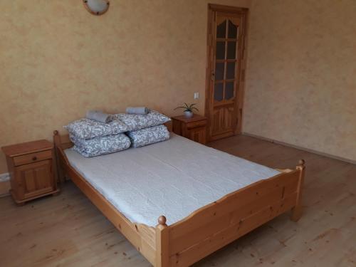 a bedroom with a wooden bed with pillows on it at Brālēni in Tūja