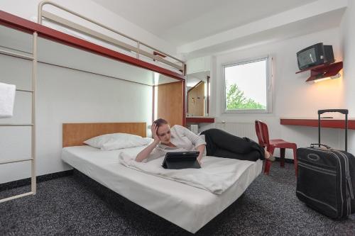 a woman laying on a bed with a laptop at bon marché hôtel Bochum in Bochum