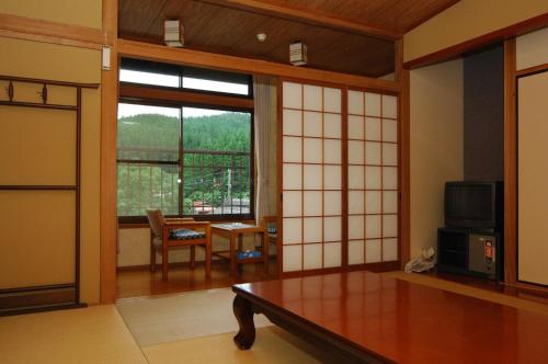 a living room with a table and a window at Ryokan Yunosako in Minamioguni