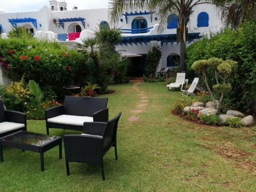 a yard with chairs and a house with blue and white at Villa à Bouznika Bay-plage et golf in Bouznika