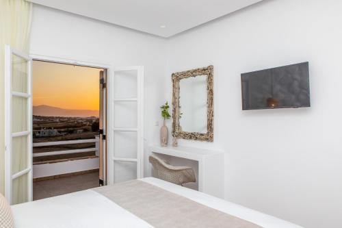 a white bedroom with a bed and a mirror at Naxian Pearl in Mikri Vigla