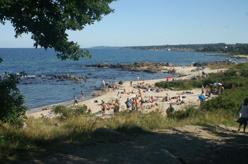 a group of people on a beach near the water at Sandkaas Family Camping & Cottages in Allinge