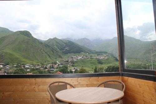 a table and chairs in front of a window with mountains at Rustaveli st11 in Stepantsminda