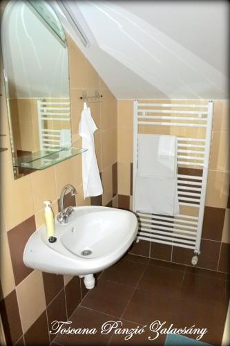 a bathroom with a white sink and a mirror at Toscana Panzió in Zalacsány